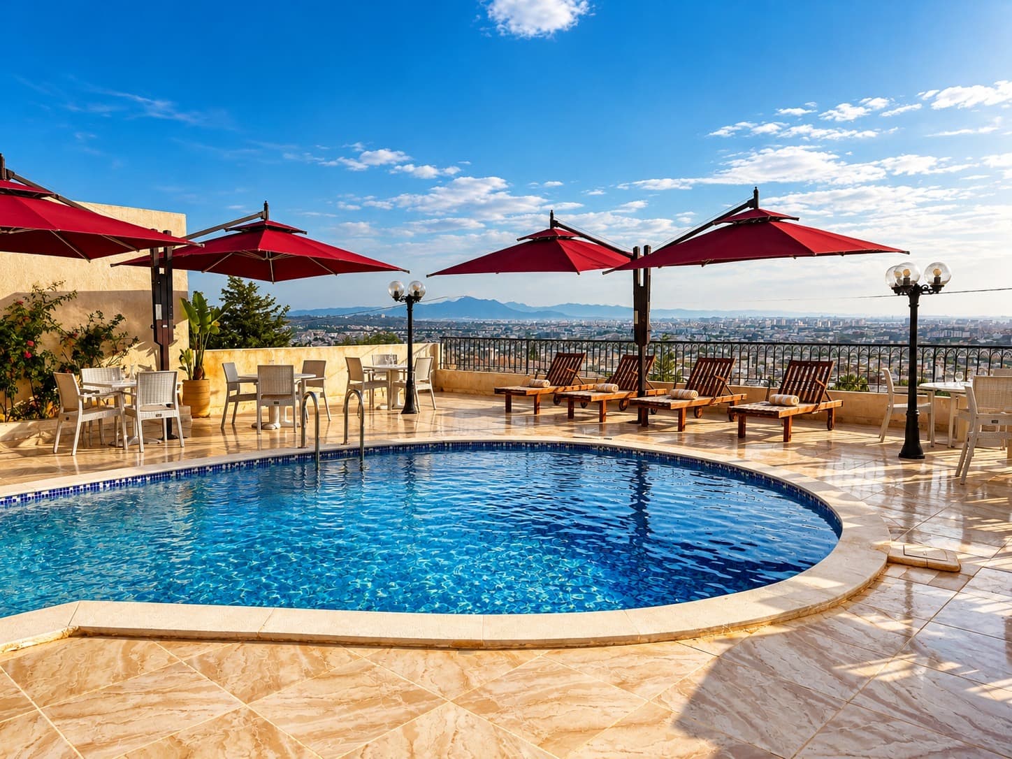 Piscine sur la terrasse avec parasols bordeaux, transats en bois et vue panoramique sur la ville