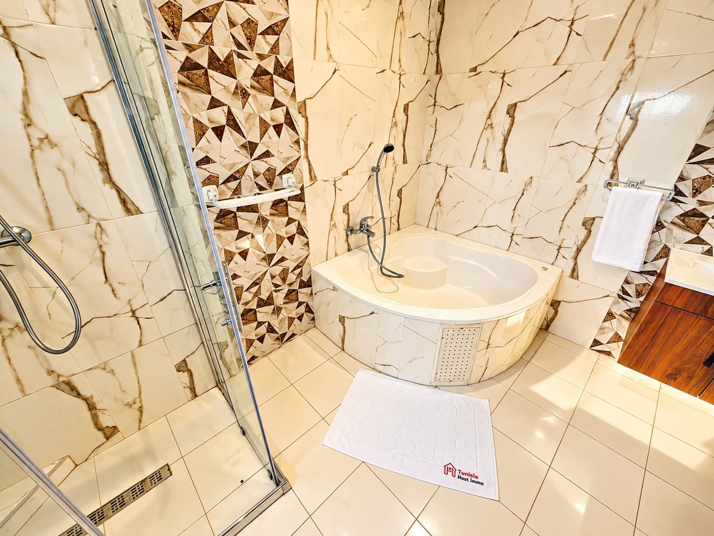Salle de bain en marbre blanc veiné avec baignoire d'angle et cabine de douche vitrée